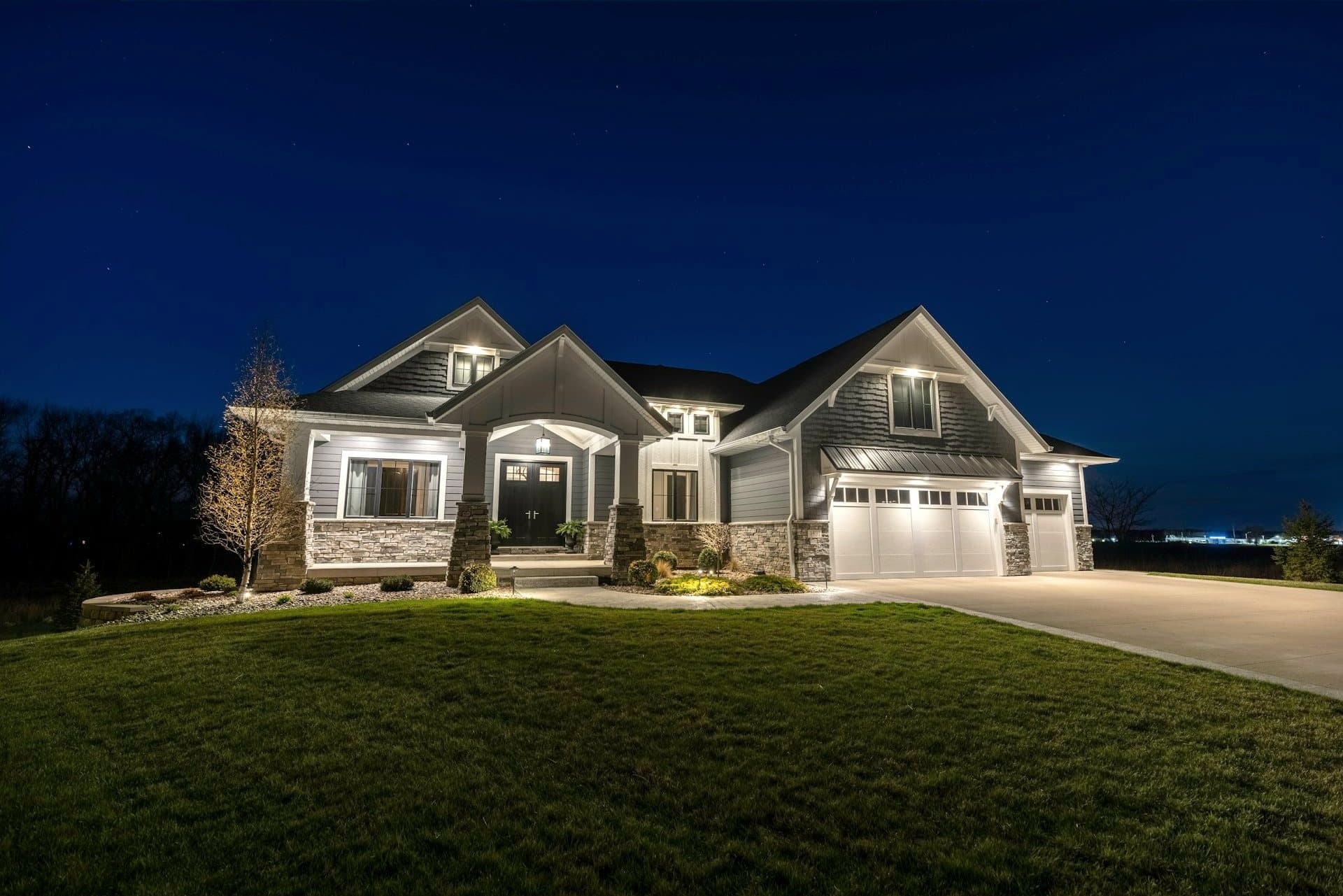 A stone and shingle estate home illuminated at night