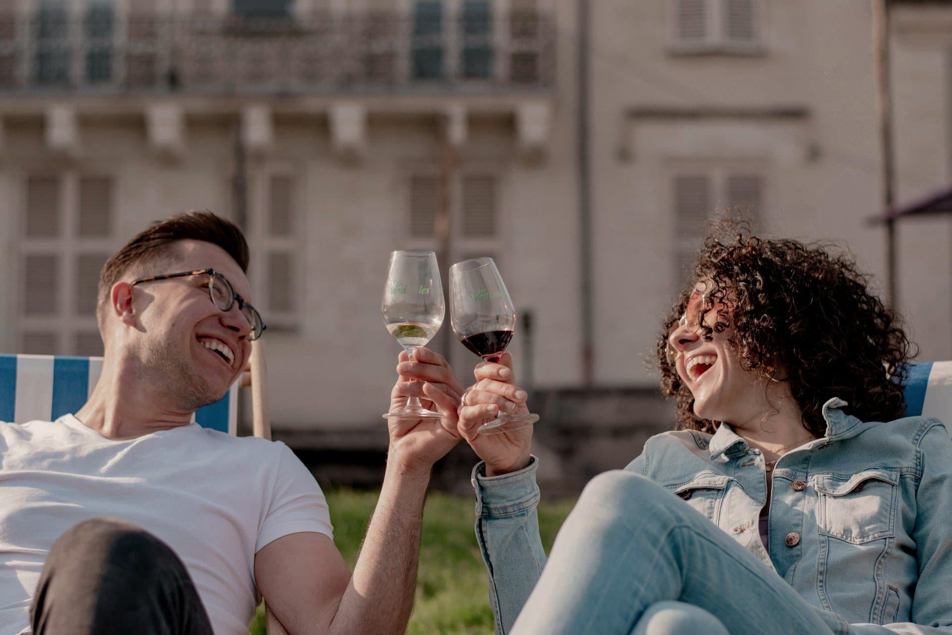 A couple laughing and raising a glass on the lawn of their home