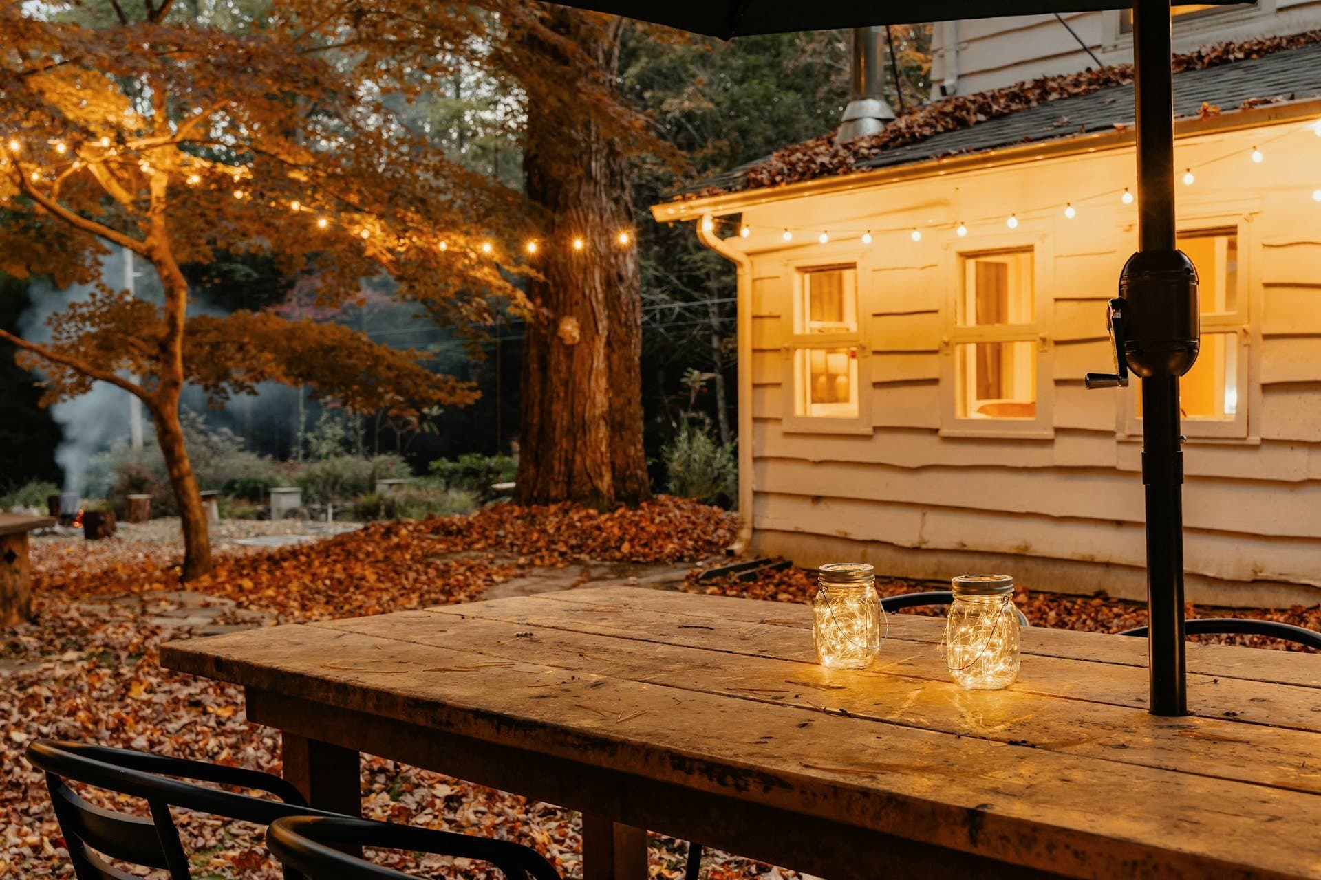 A candlelit patio table under string lights on an autumn evening