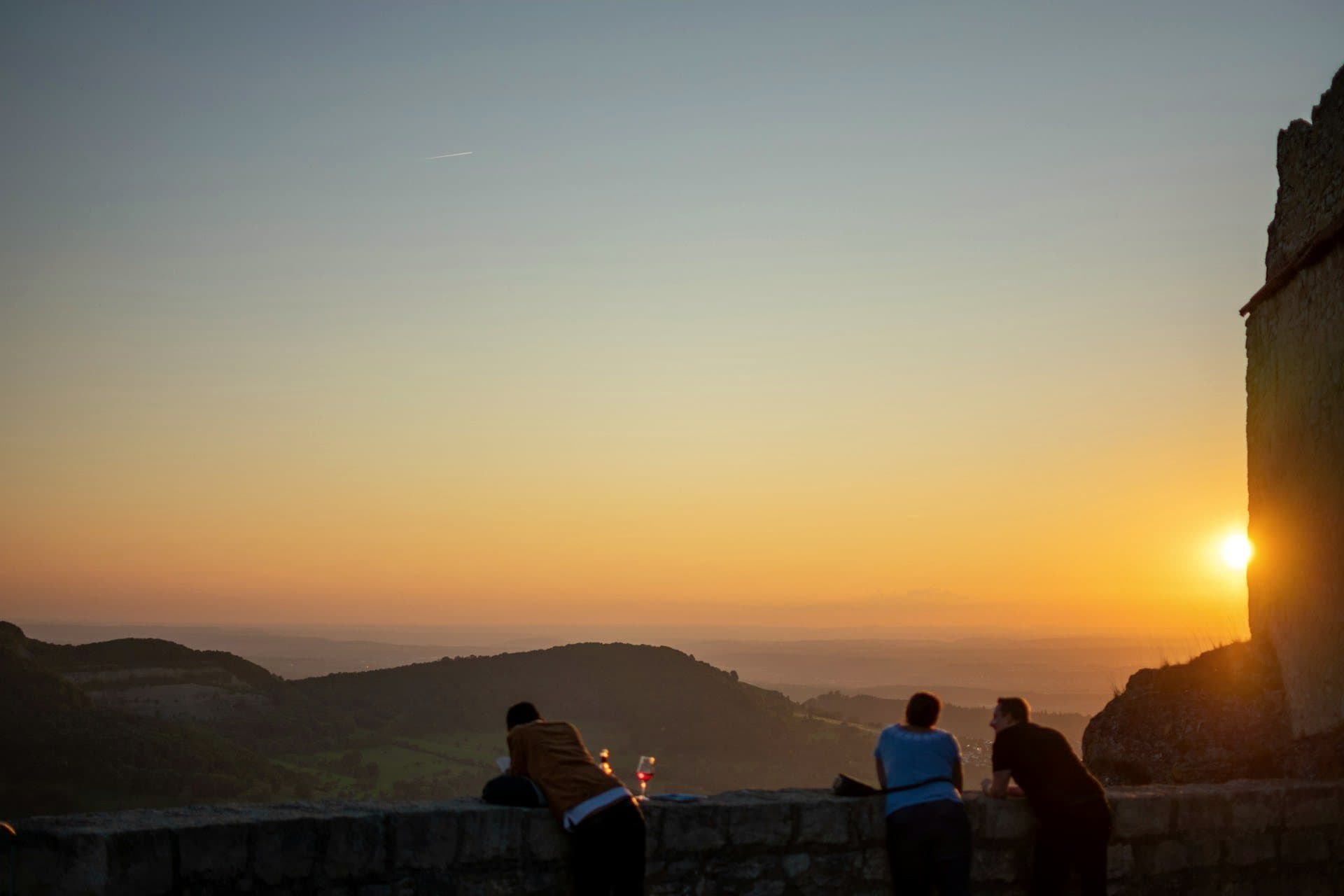 Friends watching the sun set over a wide valley view