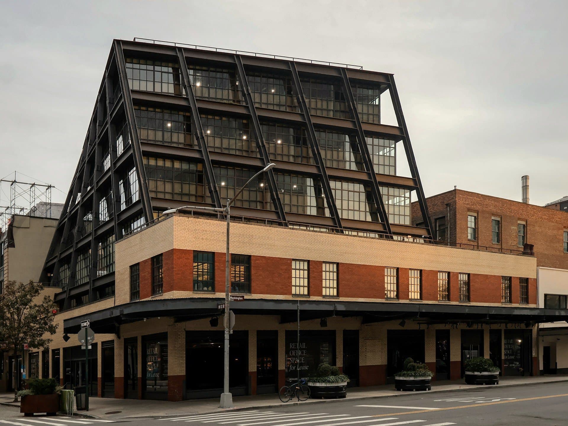 A steel-framed mixed-use building rising above a brick corner block